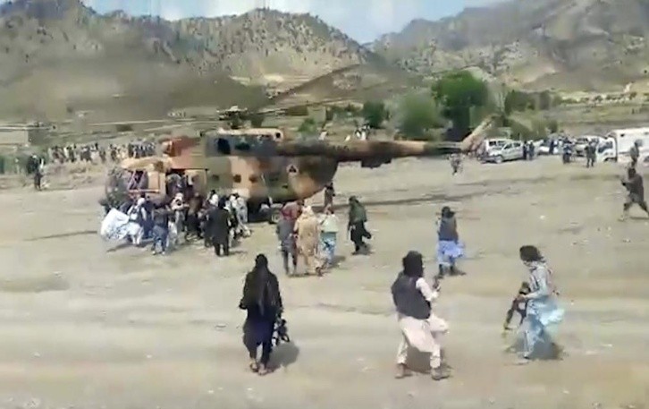 Men using blankets to carry the wounded onto helicopters. AP